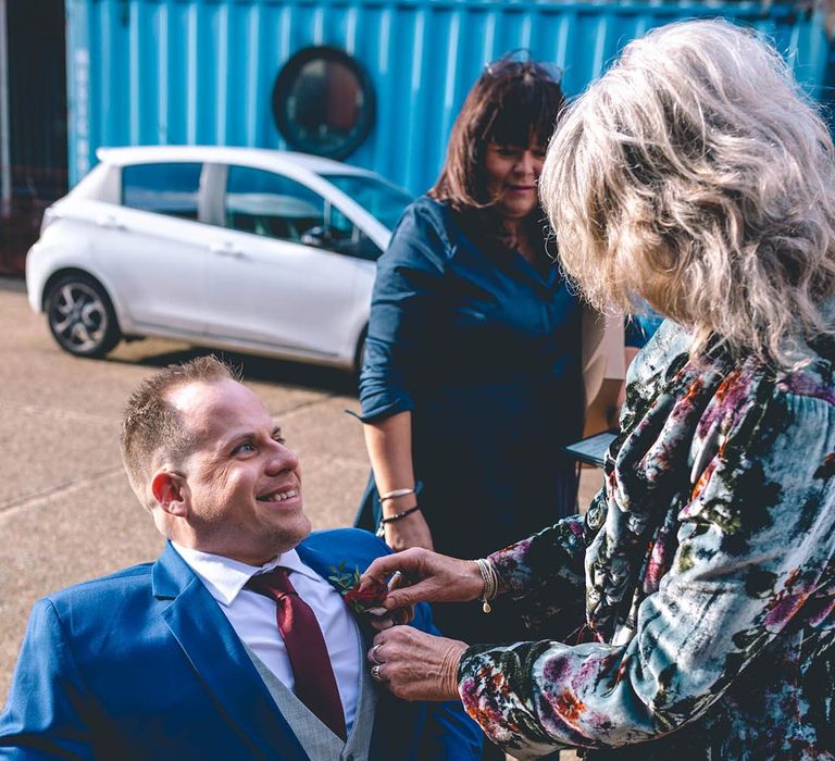 Groom in wheelchair wearing blue suit with floral buttonhole