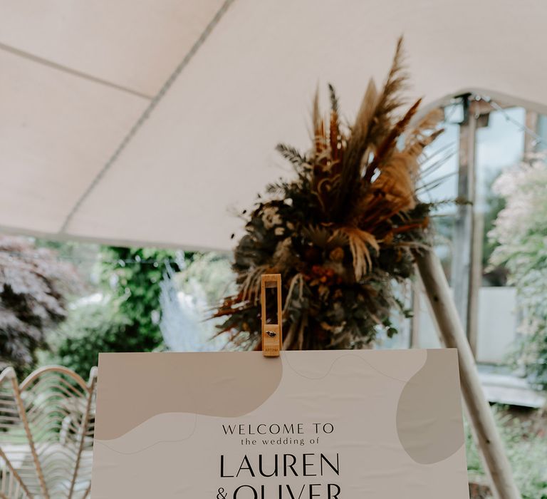 Wedding welcome sign on a wooden easel with stone, orange and green design 