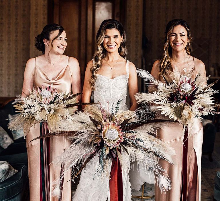 Bridesmaids wear silk dresses whilst holding bold statement bouquets with the bride