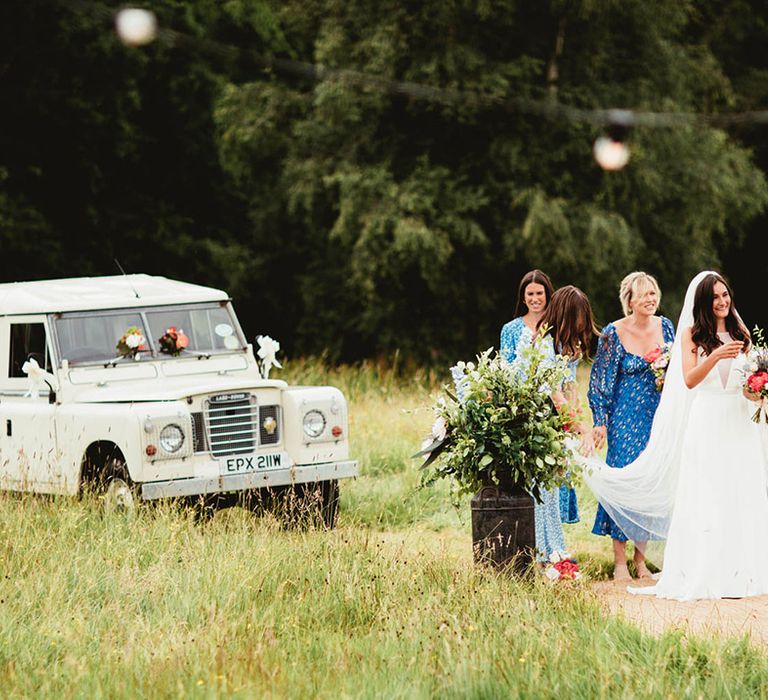 Bride walks away from Defender whilst carrying floral bouquet