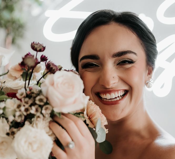 Bride smiles and holds floral bouquet