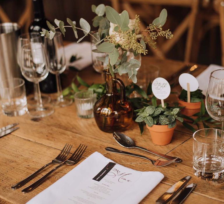 Wedding table place setting with foliage decor and plant place names