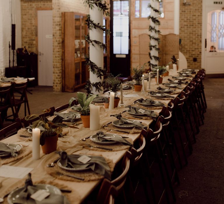 Venue with disco ball and vine details with long wooden banquet tables complete with green plates and napkins and wicker placemats 