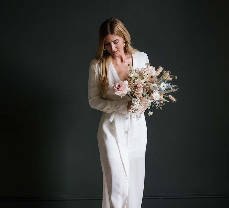 Bride in long sleeve buttoned white wedding dress with plunging neckline and gold mules