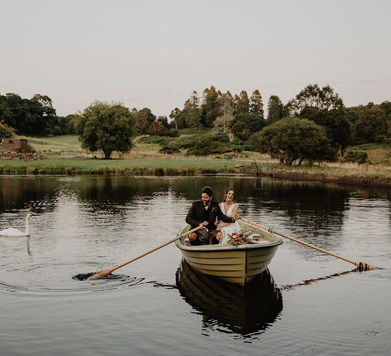 Bride and groom take a ride in the row boat across the loch at Cardney Estate wedding venue