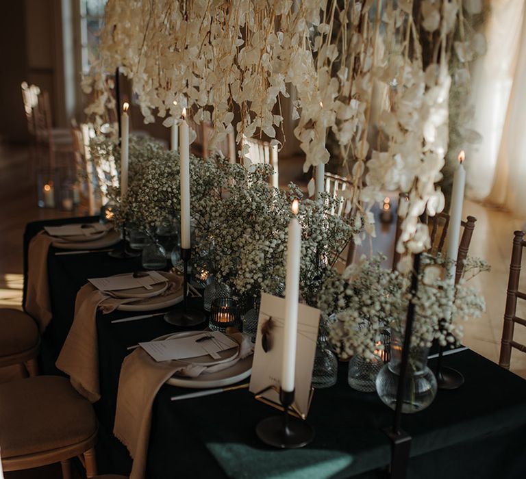 Luxury tablescape at Hodsock Prory with hanging flower installaion and gypsophila centrepiece flowers on a black table cloth 