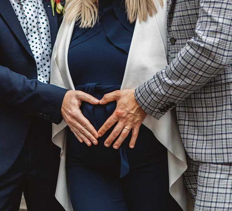 Grooms make a heart shape around their surrogates belly 