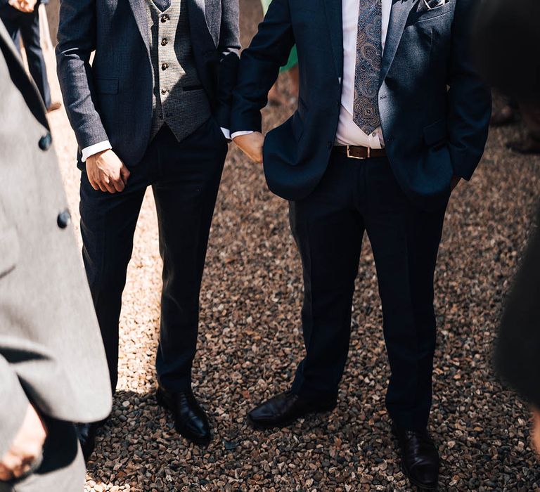 Groom wears matching dark blue suit as groomsman with matching paisley ties and handkerchiefs