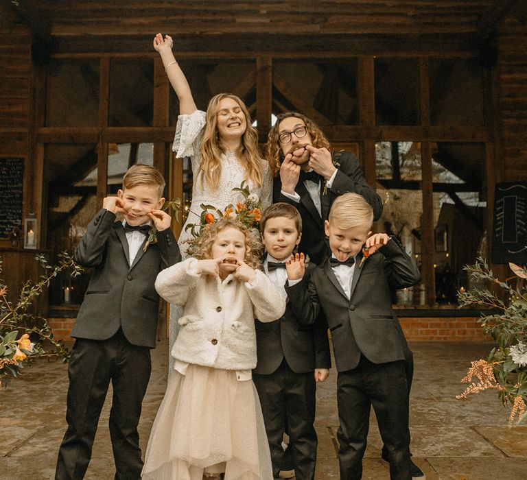 Bride and groom pull funny faces with their nephews and niece as flower girl and mini groomsmen