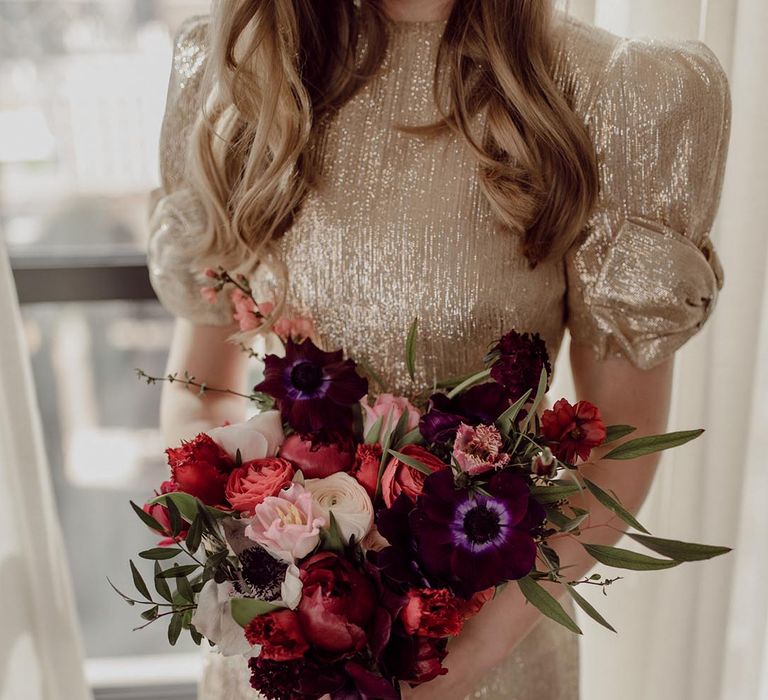 Bride in sparkly wedding dress holding pink, red and purple flower wedding bouquet