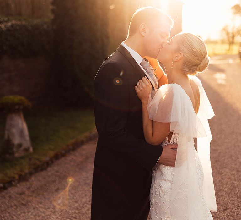 Golden hour couple portrait of bride and groom as they kiss