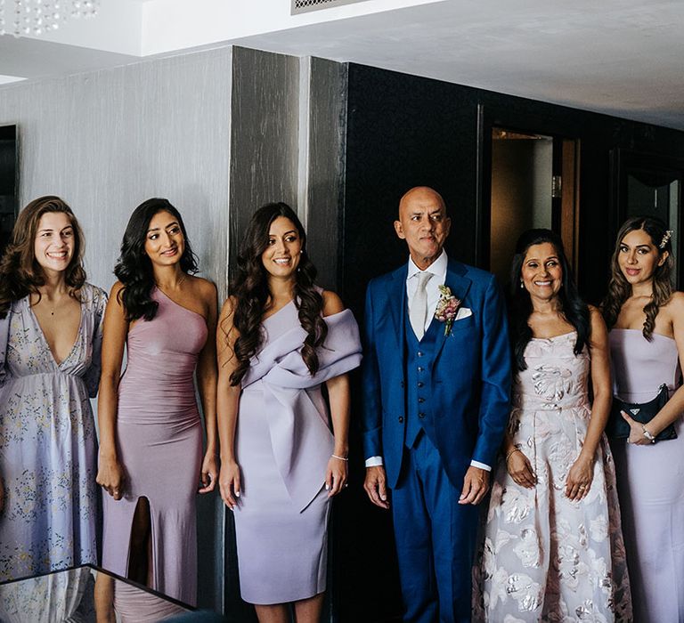 Bridesmaids wearing lavender bridesmaid dresses stand with brides family on the morning of wedding day at Syon Park