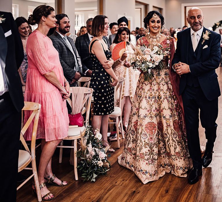 Bride walks down the aisle with her father for multicultural wedding at Bredenbury Court Barns