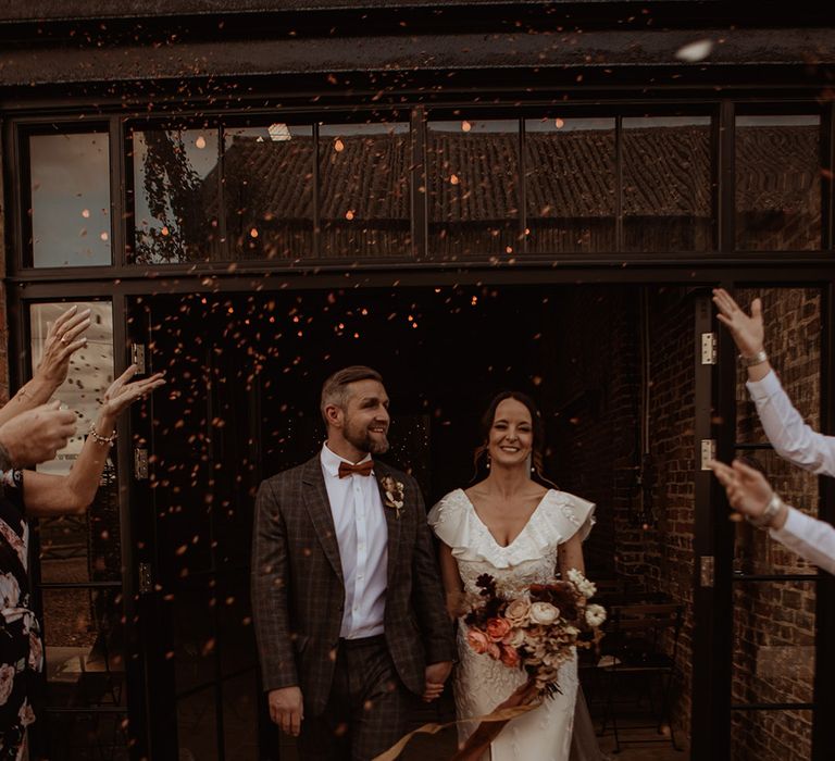 Bride and groom have a confetti moment as they exit from their rustic luxe barn wedding 