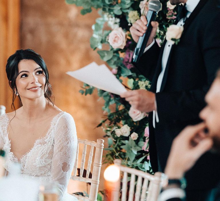 The bride looks up lovingly at the groom as he reads out his wedding speech 