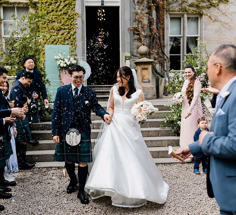 Bride & groom in green tartan kilt walk through white confetti exit at Carlowrie Castle 