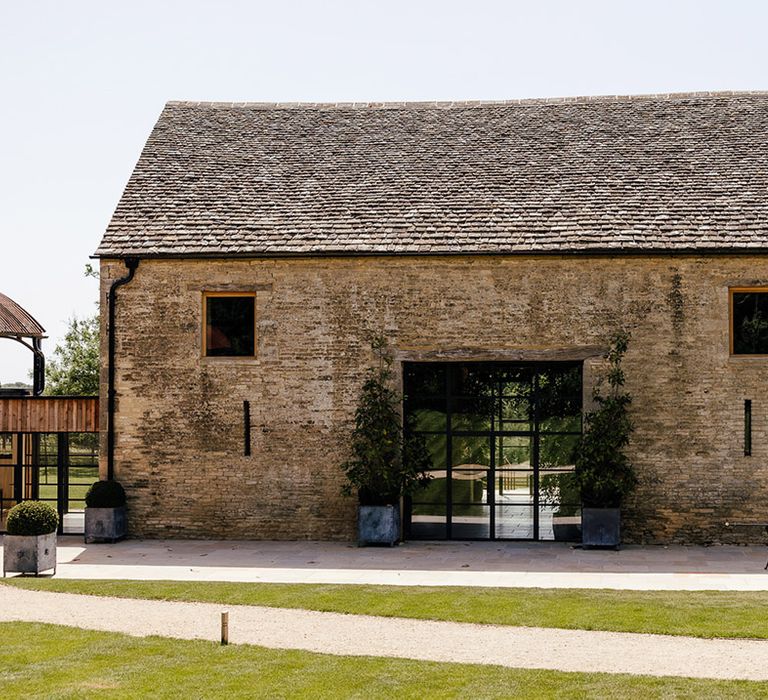 Old Gore Barn wedding venue exterior with large plant pots and black, modern windows