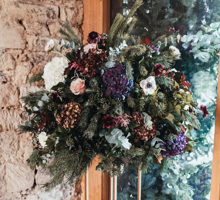 Blue, white, and red winter wedding flower arrangements made up of roses, anemones, and hydrangea 