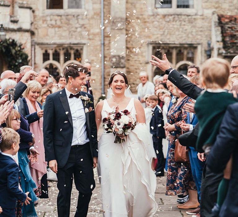 Bride and groom laughing together as they have a confetti exit together from their civil ceremony at Notley Abbey 