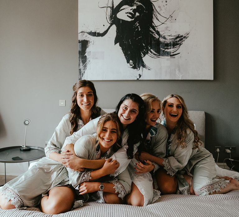 Bride sits and embraces her bridesmaids in matching pyjamas on the morning of her wedding day