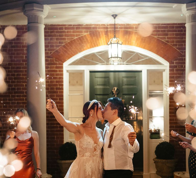 Bride & groom kiss surrounded by sparklers during outdoor sparkler exit