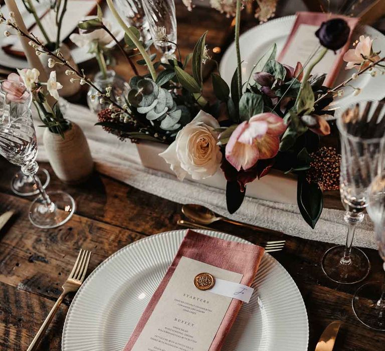 Dusky pink cotton napkin on minimalistic wedding menu with gold cutlery and rose, carnation, eucalyptus, dried flower and baby's-breath floral arrangements 