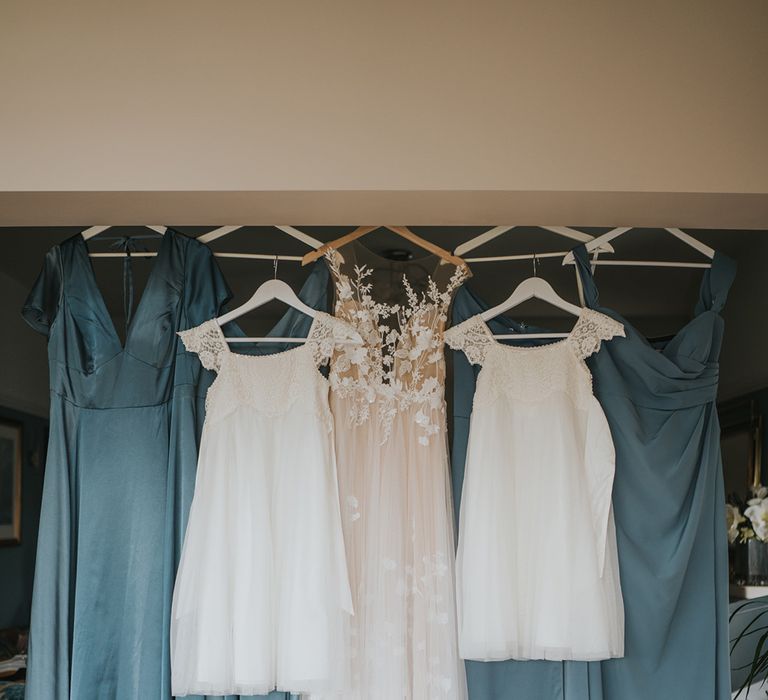 Blue bridesmaid dresses hanging up with the bride's Anna Kara wedding dress and two white flower dresses 