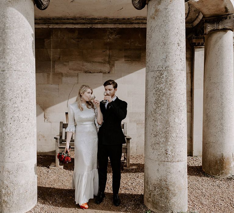 The bride and groom sip champagne from their coupe glasses for Halloween wedding at Normanton Church