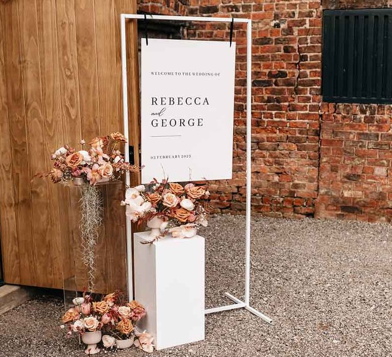 Minimalistic white wedding sign on white frame with blush garden rose, dried flower and pink peony floral arrangements at Lodge Farm wedding venue 