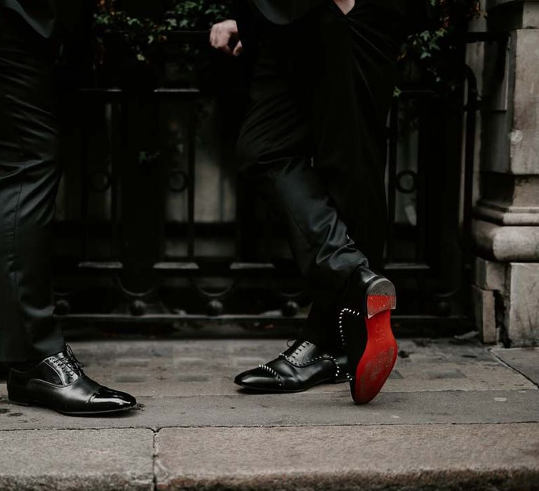 Grooms in matching black tie trousers and studded Christian Louboutin grooms shoes showing the red sole 