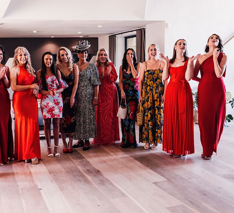 Bridal party and other wedding guests wearing red bridesmaid dresses and other floral dresses 