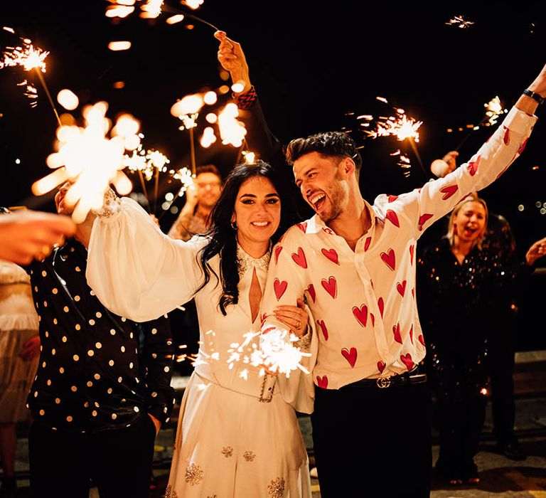 Sparkler send off with bride in sparkly jumpsuit and groom in heart patterned shirt