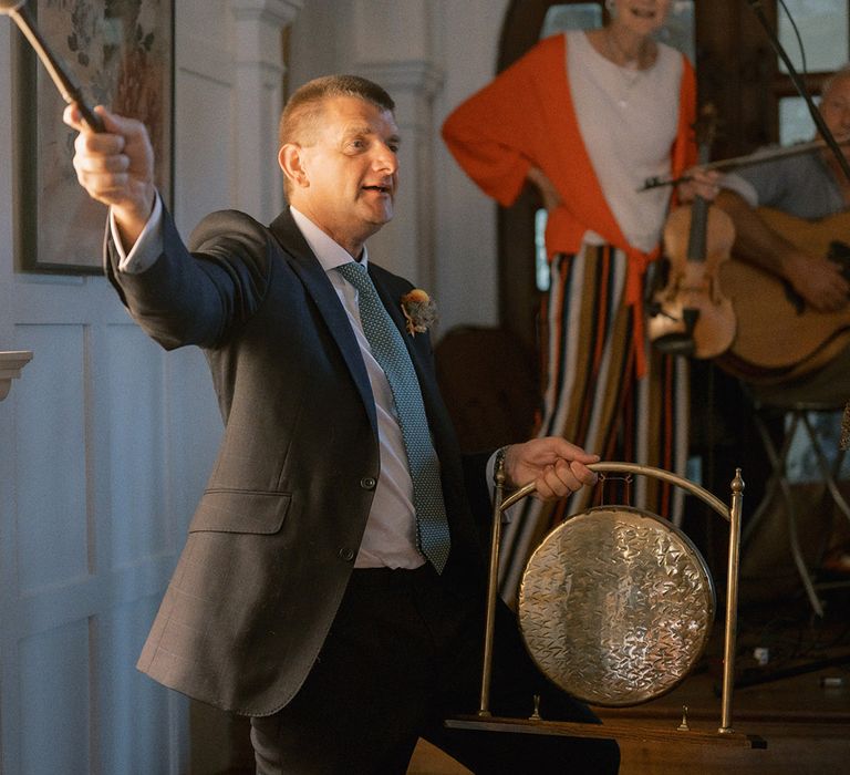 Man in suit banging a gong for the Chinese Tea Ceremony 