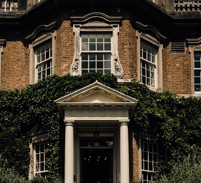 Hampton Court House wedding venue in Surrey with the bride and groom walking out of their ceremony as a married couple 