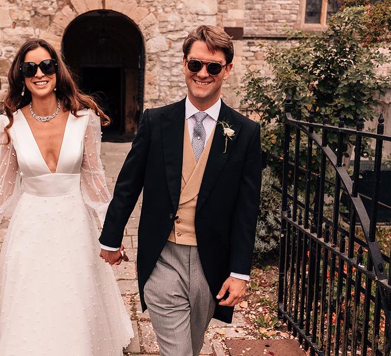 The bride and groom pose for couple portraits around their wedding venue with black sunglasses accessories 