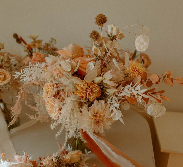 Autumnal orange wedding bouquet tied with dried wedding grass 