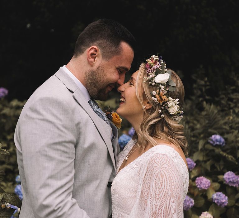 Bride in boho gown with wildflower wedding crown gazing into the groom's eyes 