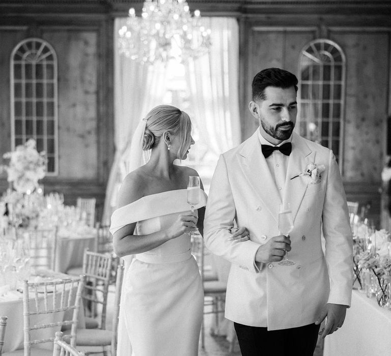 Groom in white double breasted suit jacket with bride in off the shoulder wedding dress by Eva Lendel 