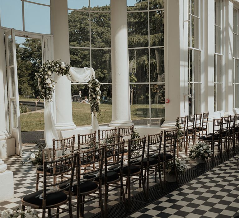 Gunnersbury Park wedding ceremony room with drapes and floral arch altar decoration 