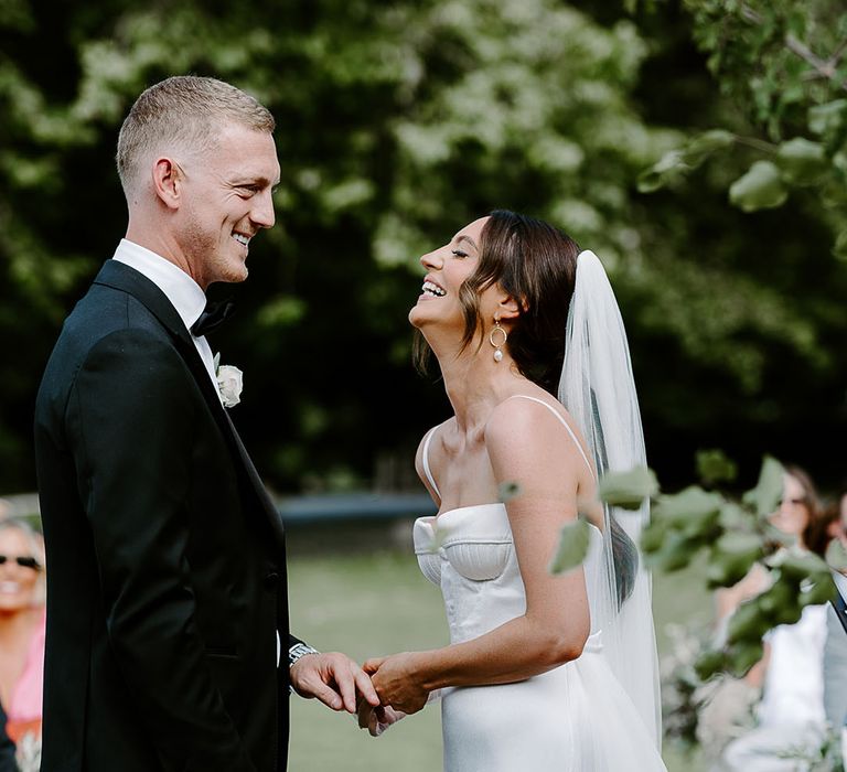 Babington House outdoor wedding ceremony with the bride and groom laughing together 