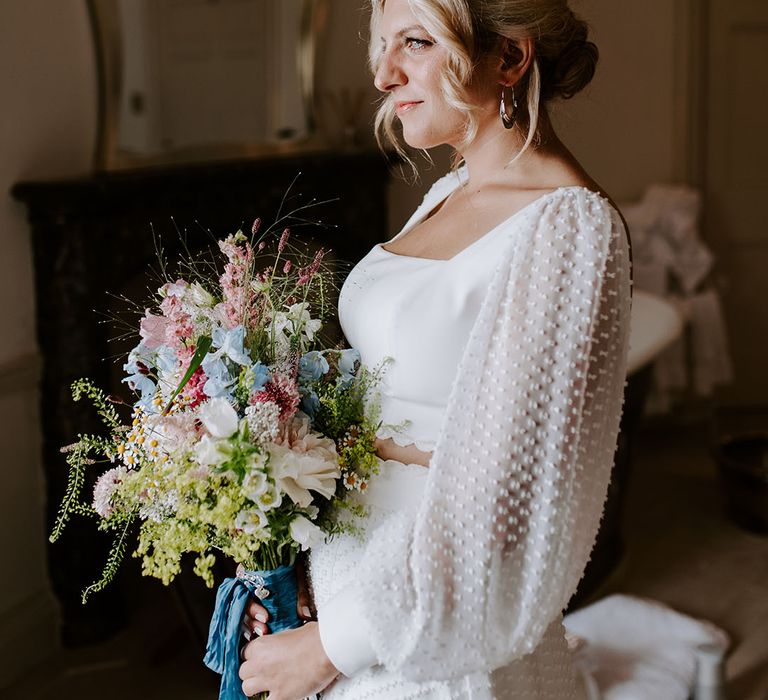 Bride in spotted long sleeve bridal top and skirt separates holding pastel wildflower wedding bouquet 