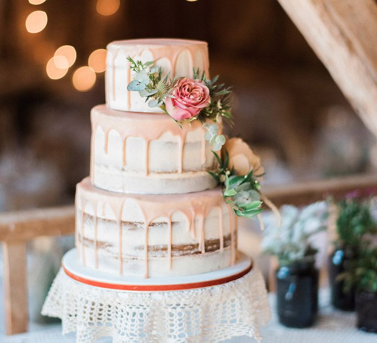 Three tier semi-naked wedding cake with peach drip icing with pink and orange peach roses 