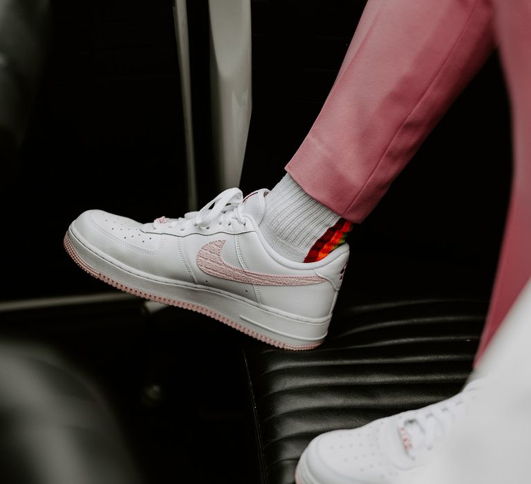 The groom wears pink trousers with custom white and pink Nike Air Force trainers 