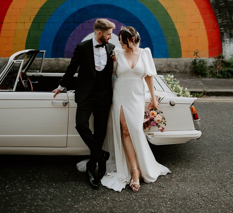 Rainbow backdrop at urban city wedding with bride and groom posing for couple portrait 