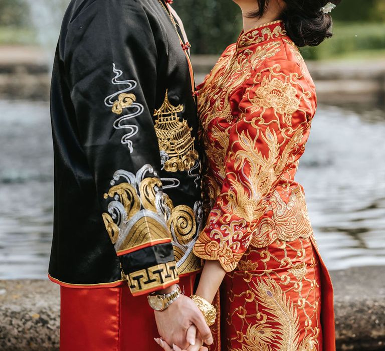 Bride in red and gold Chinese wedding attire gazing up at the groom as they pose for a cute couple portrait 