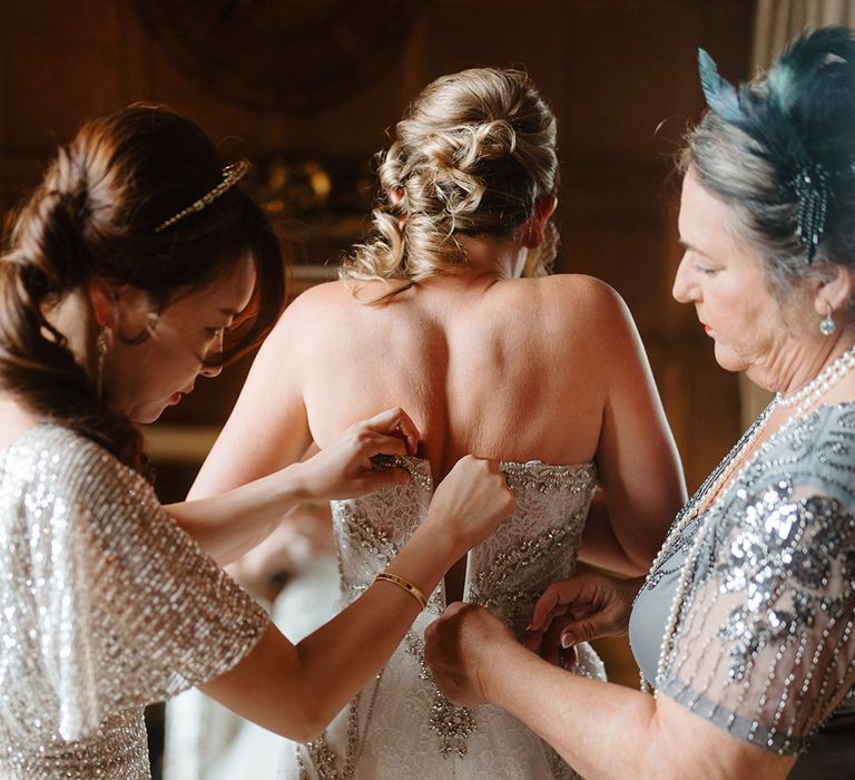 Bride getting zipped up into a embellished mermaid wedding dress by Badgley Mischka 