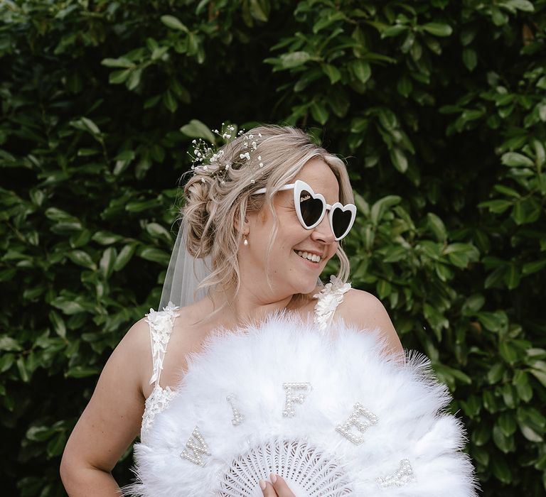 Bride with white feather fan accessory for the with retro sunglasses 