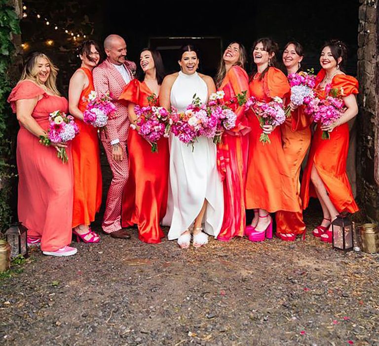 bridesmaids wearing bright orange satin bridesmaid dresses with hot pink accessories