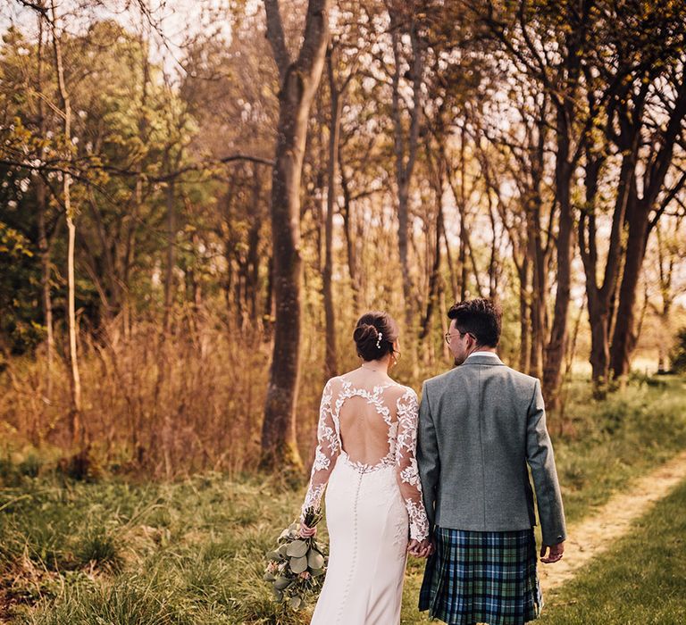 bride-wearing-lace-long-sleeve-wedding-dress-with-train-with-groom-in-tweed-suit