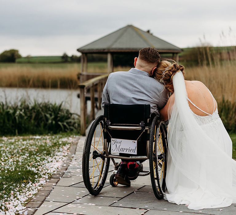 bride-rests-her-head-on-grooms-shoulder-in-wheelchair.